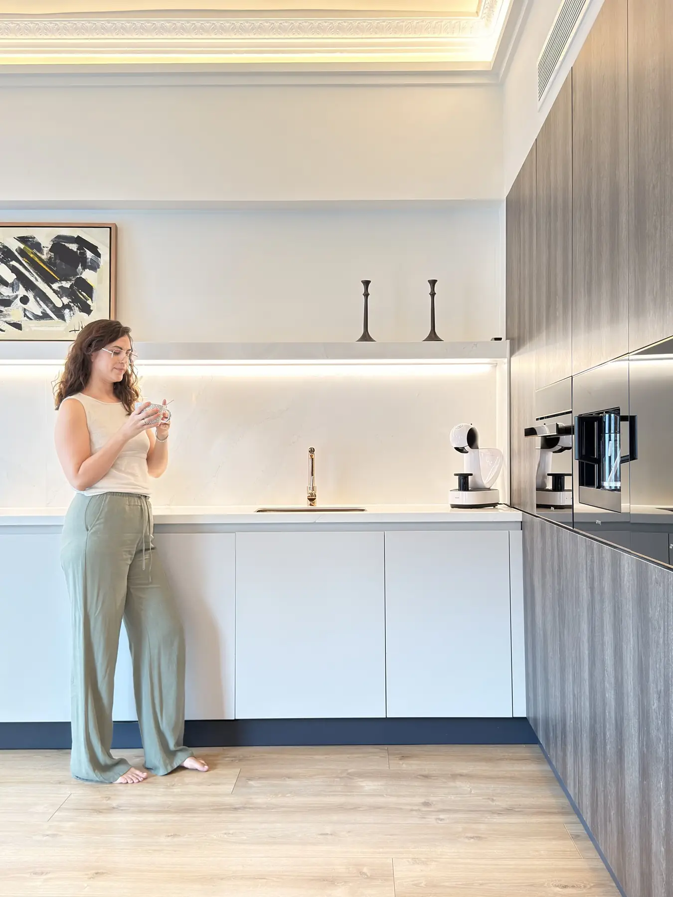 Eli en una cocina blanca sosteniendo una taza en un momento de pausa.